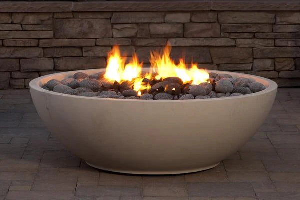 Mezzaluna gas burning fire pit with lava rock, a stone wall and concrete pavers