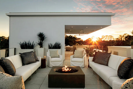 Modern rooftop fire pit with a square propane fire pit surrounded by white outdoor sofas at sunset